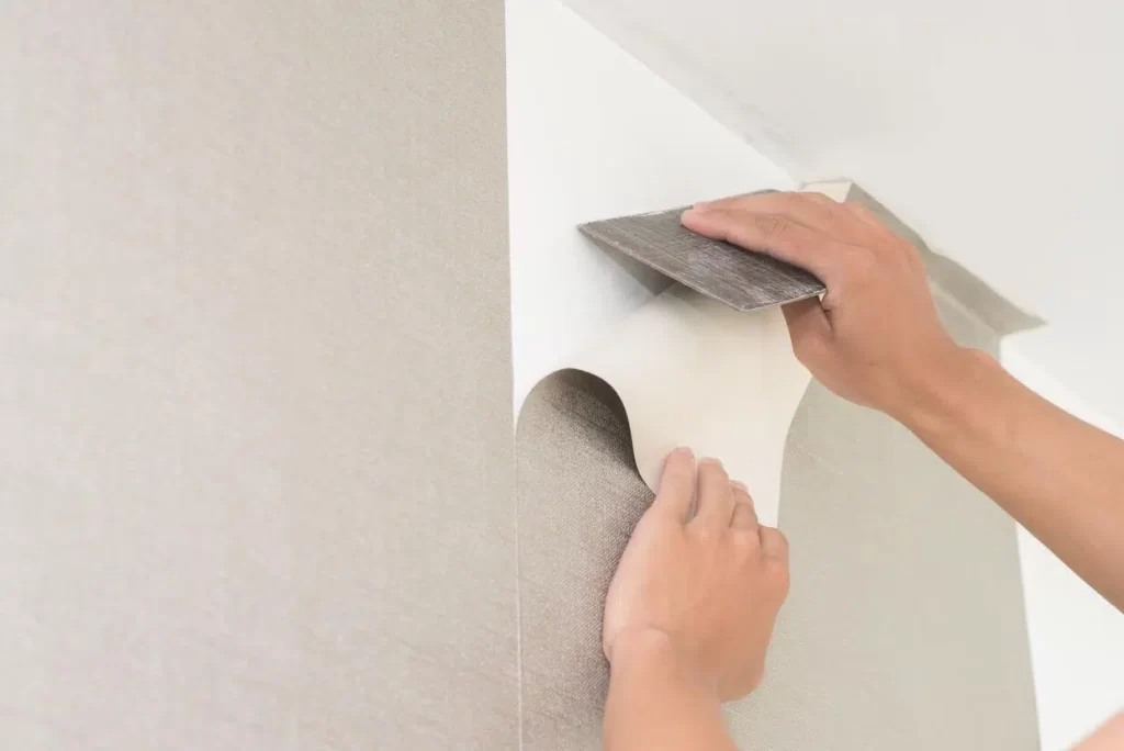 man fixing the wallpaper on the wall using sharp object for hvac contractors in dubai