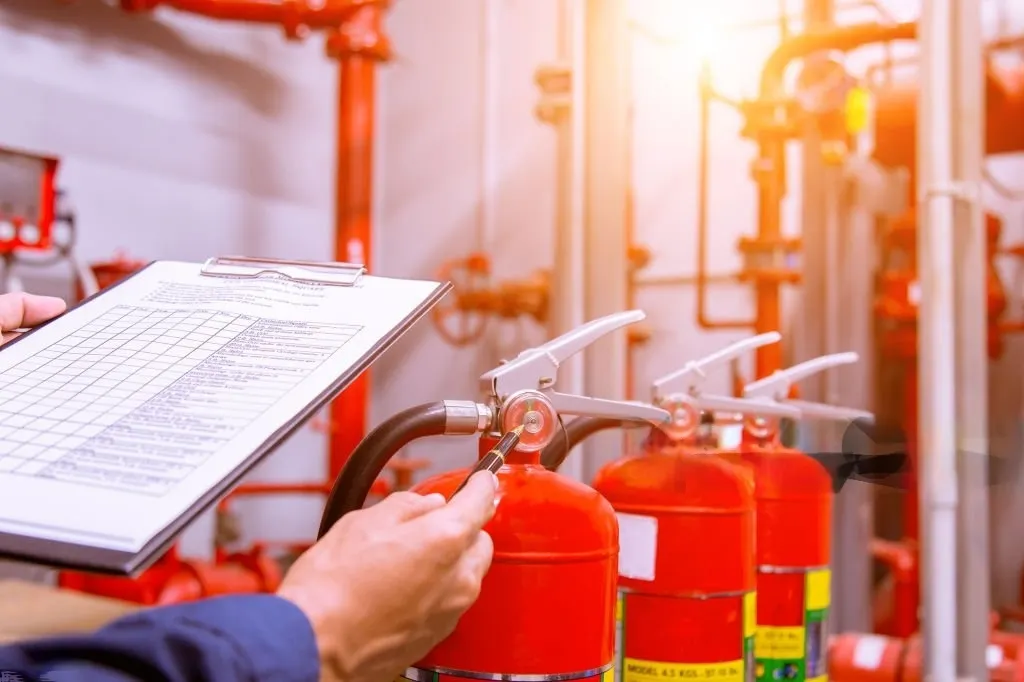 man holding a paper and checking fire extinguisher for hvac contractors in dubai